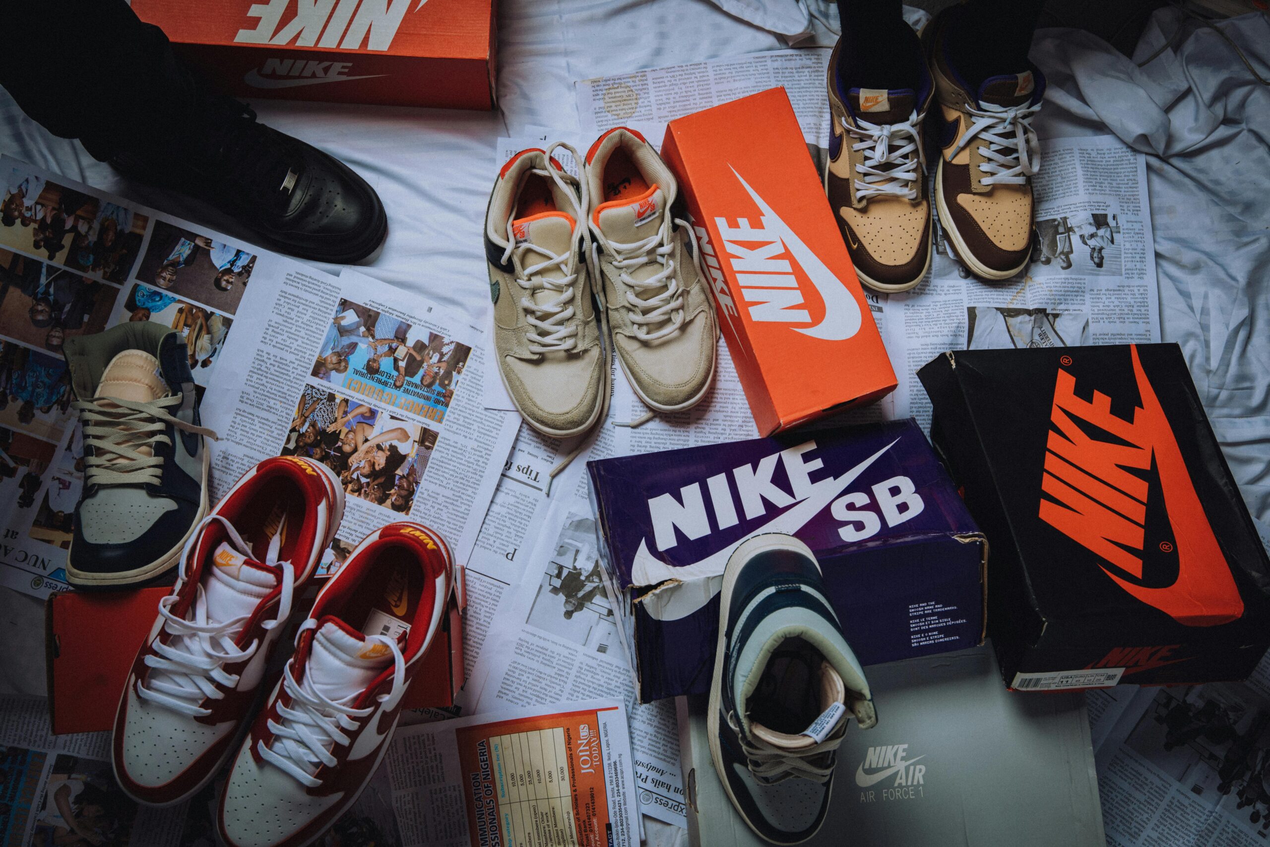 A variety of Nike sneakers displayed on newspapers with branded shoeboxes.
