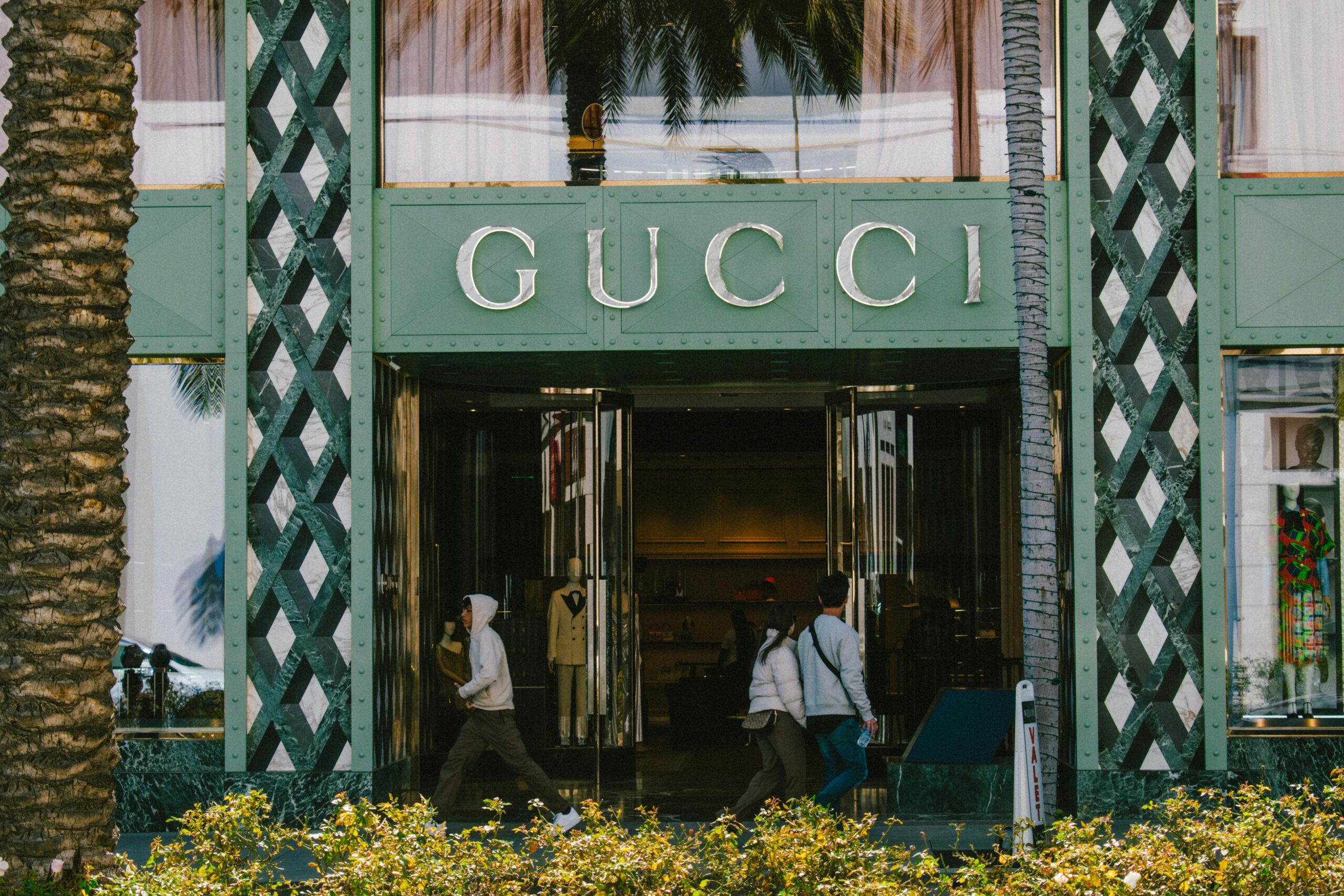 Gucci store facade with people passing by on a sunny day.