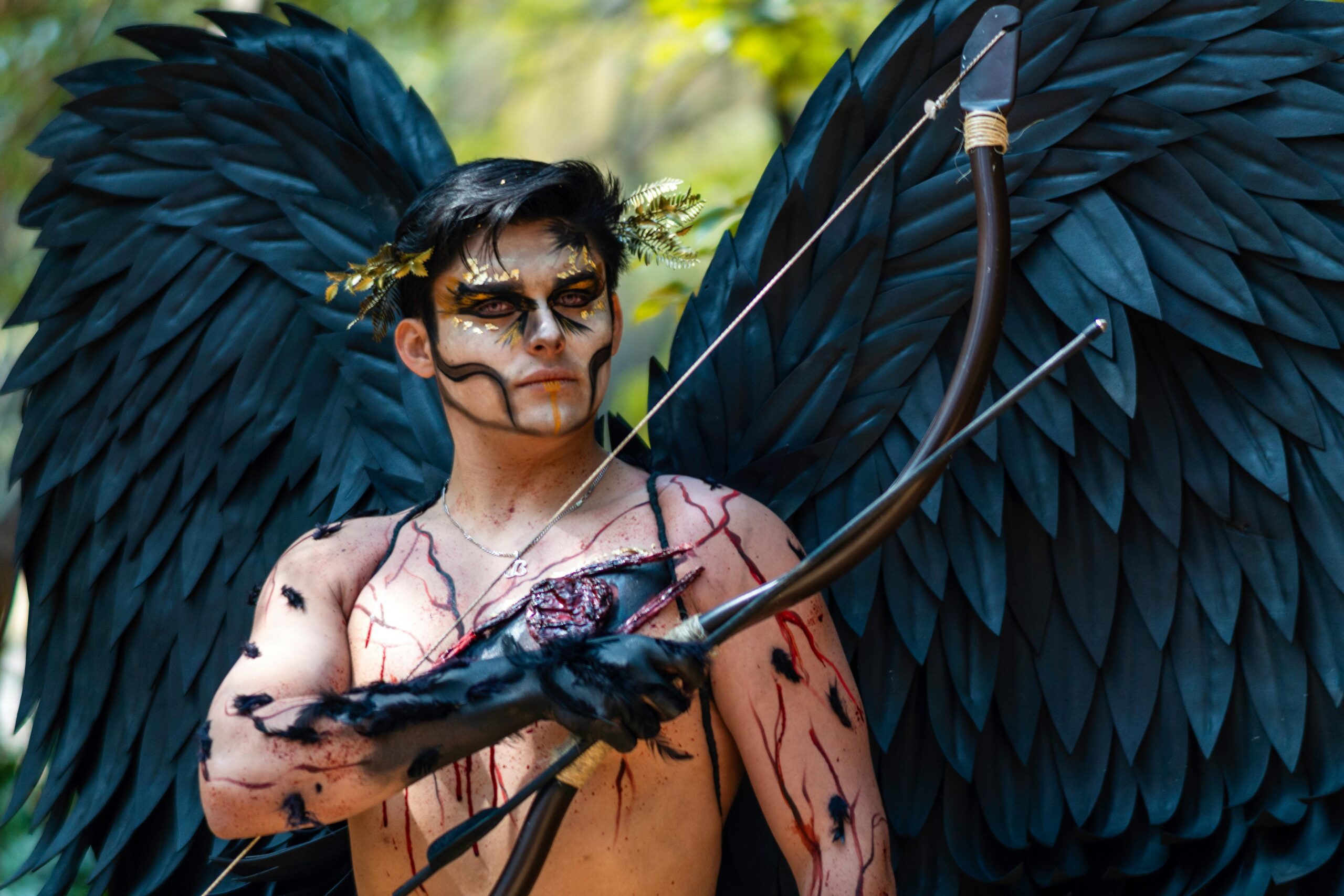 A man in costume with black wings and bow, depicting a mythical archer. Perfect for fantasy themes.