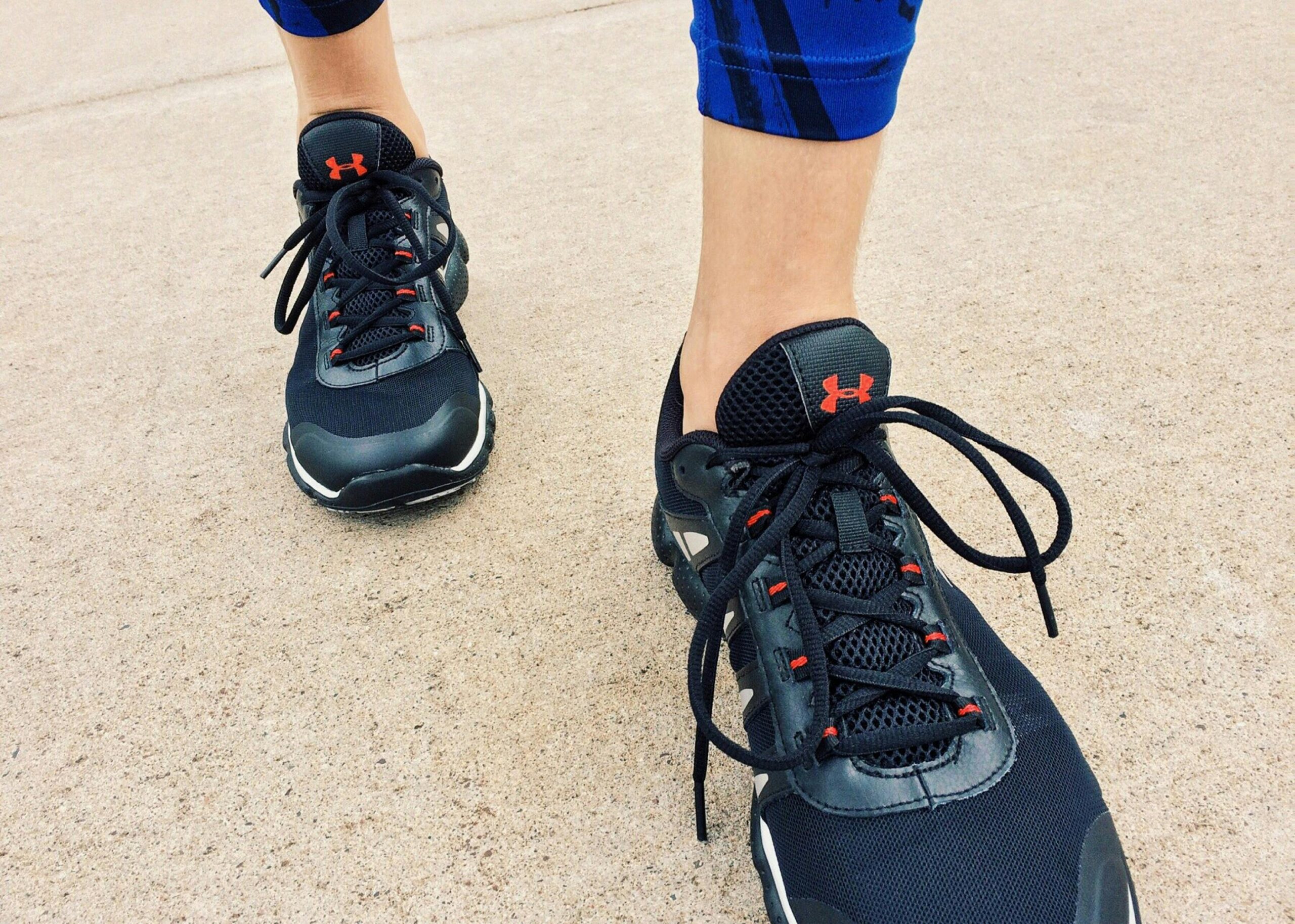 Close-up view of a person wearing black athletic sneakers on pavement, highlighting fitness and exercise.