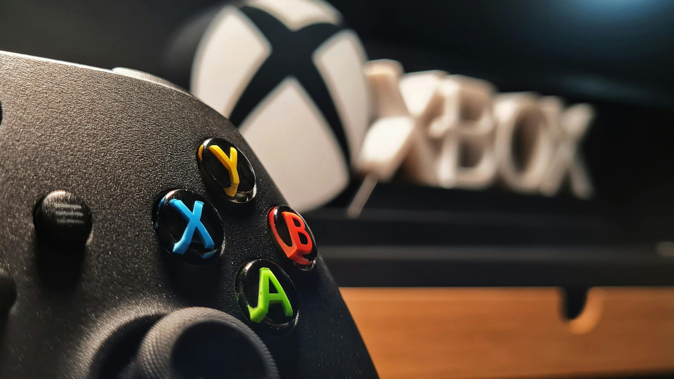 Detailed view of Xbox gaming controller with vibrant buttons displayed indoors.