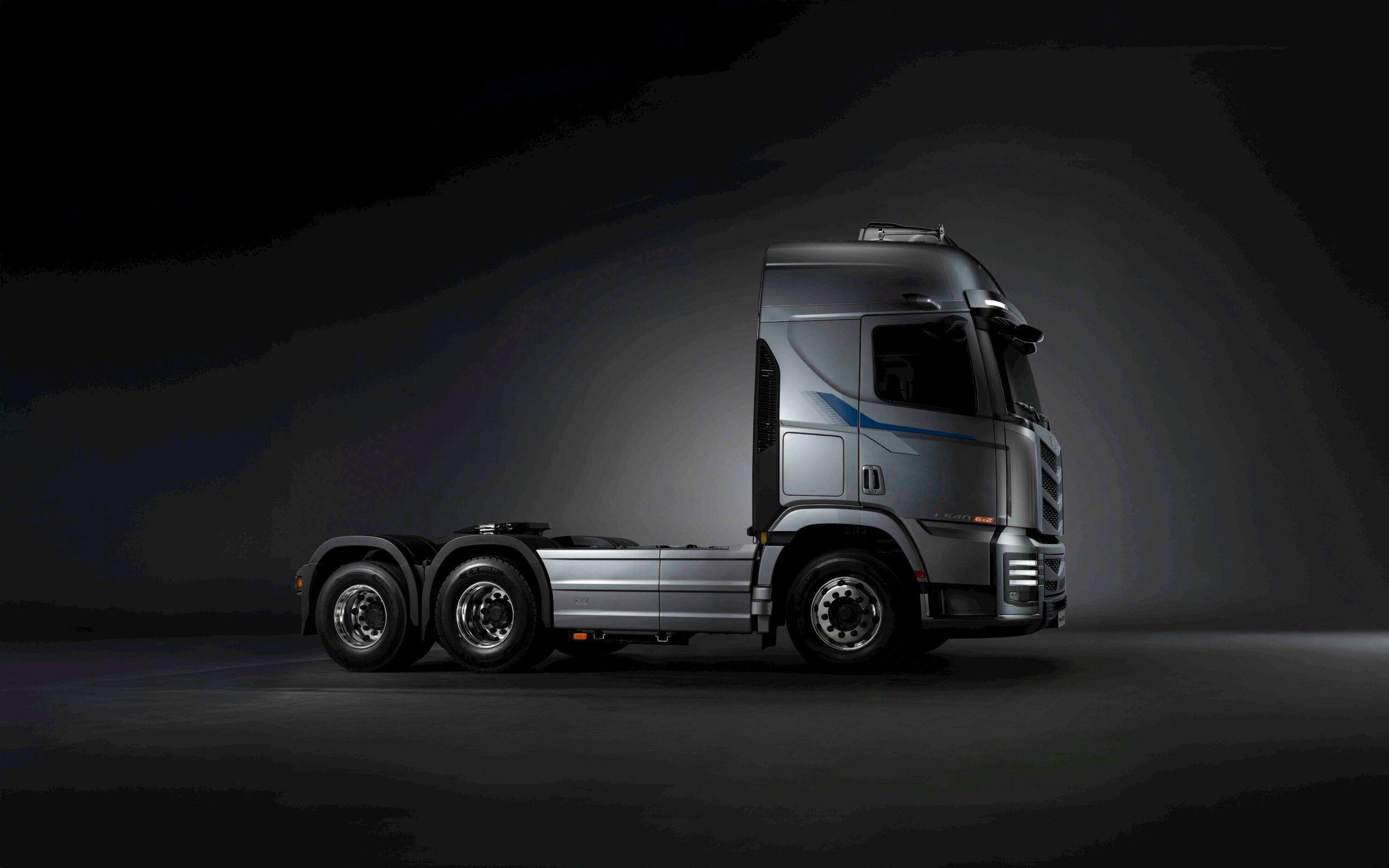 Profile view of a modern tractor trailer in a studio setting with dark background.