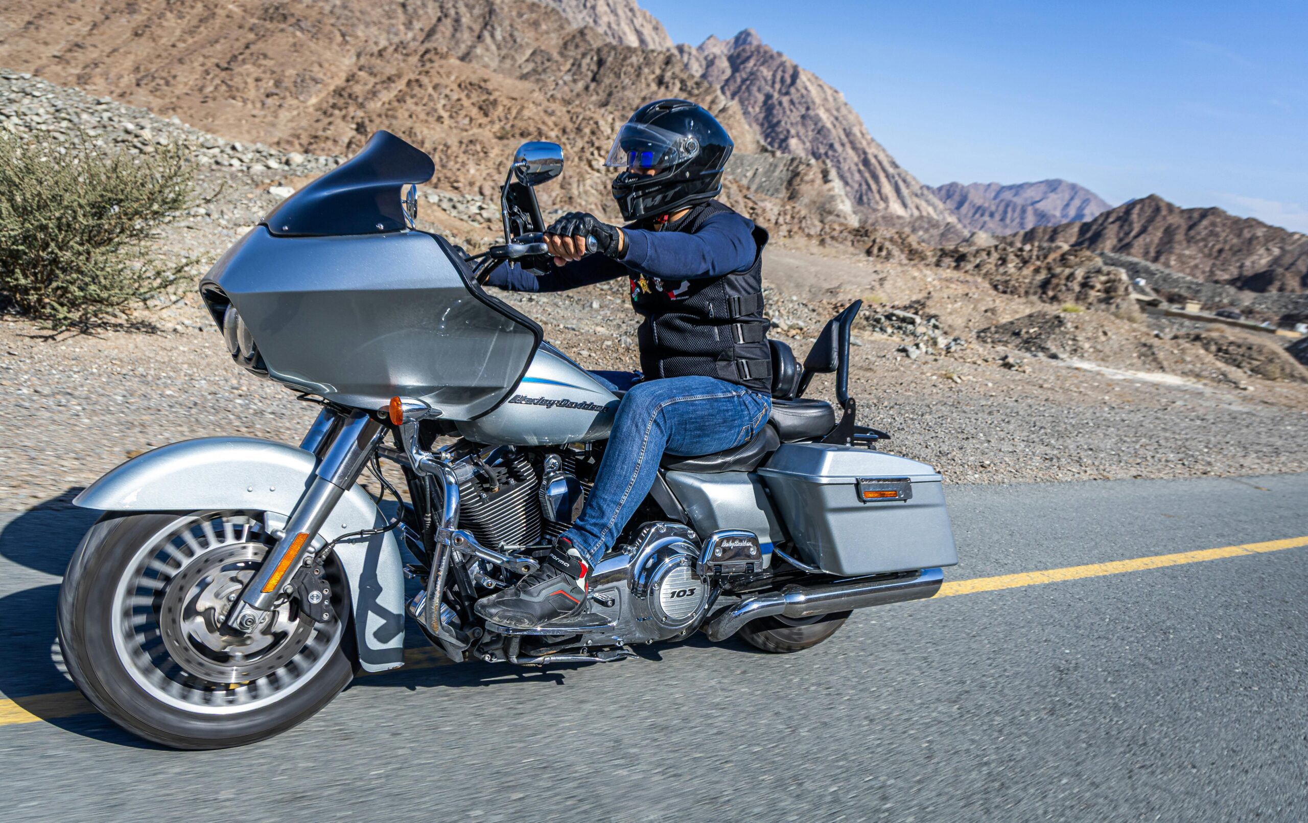 Motorcyclist cruising a Harley-Davidson through scenic Dubai mountains.