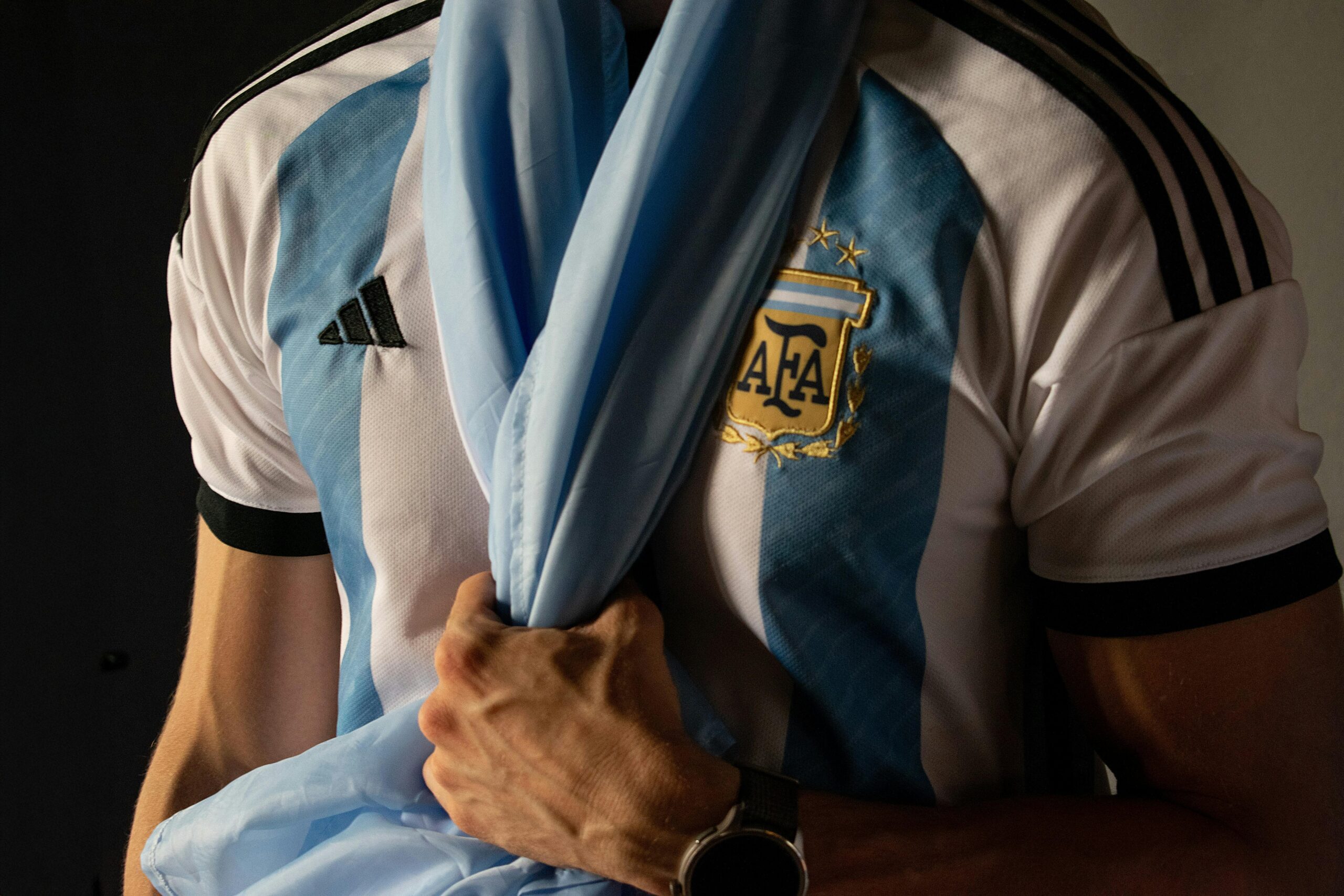 Close-up of a man holding an Argentina soccer jersey symbolizing sports enthusiasm.