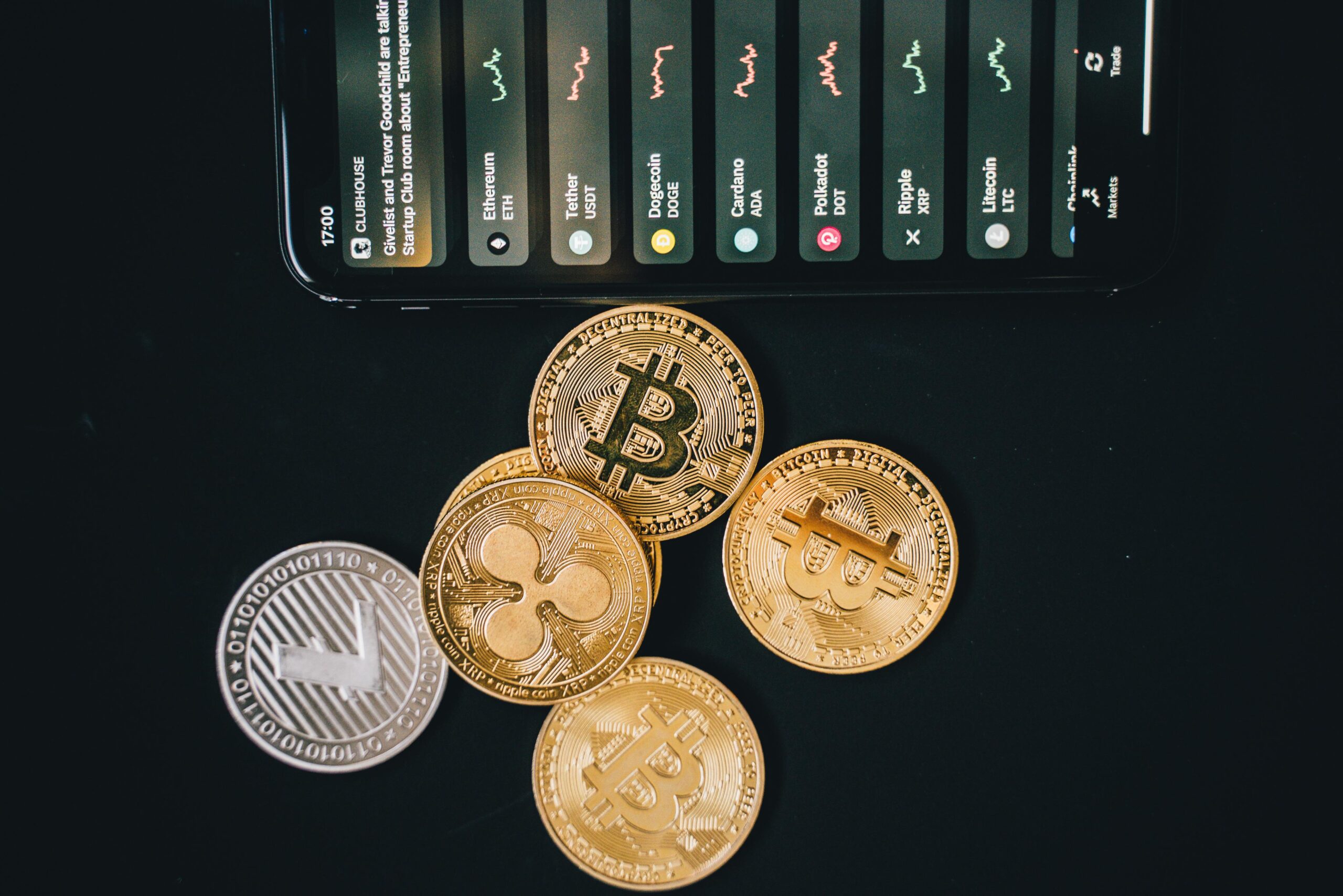 Close-up of various cryptocurrencies and a smartphone showing market trends.