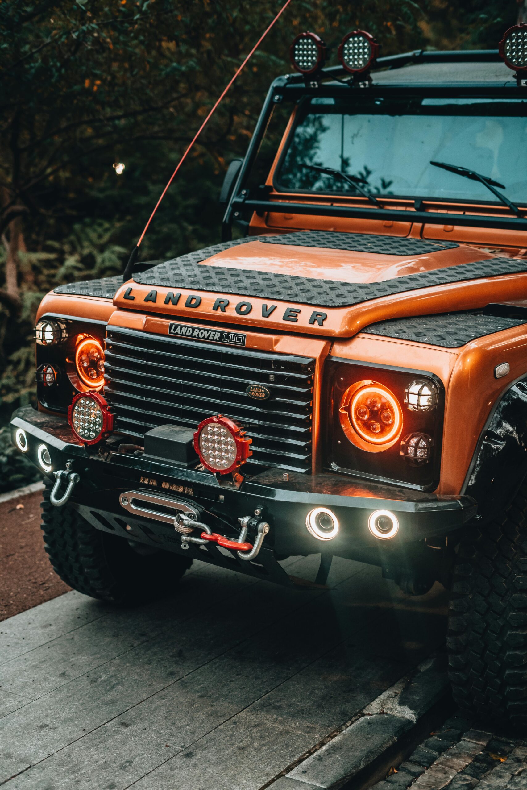 A heavily modified Land Rover Defender featuring custom headlights and rugged off-road body enhancements.
