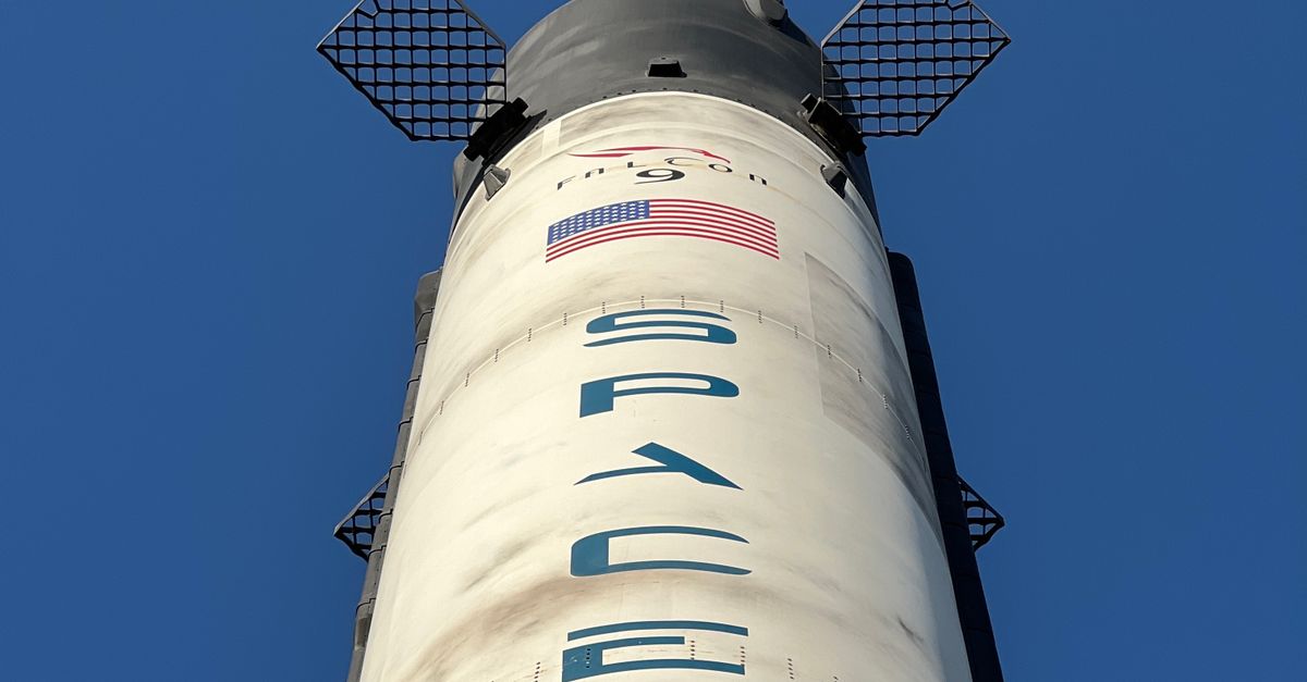 Close-up view of a SpaceX rocket against a clear blue sky, showcasing its structure and design.
