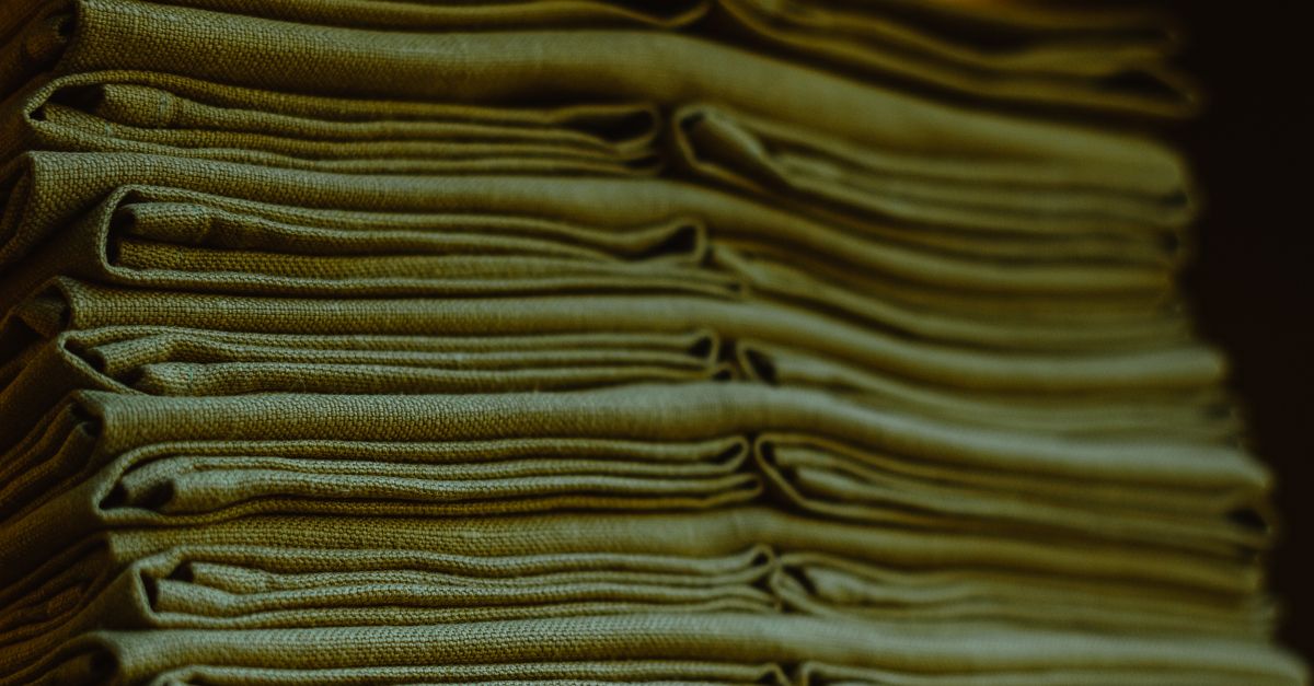Close-up of a stack of neatly folded green linens highlighting their texture and neatness.