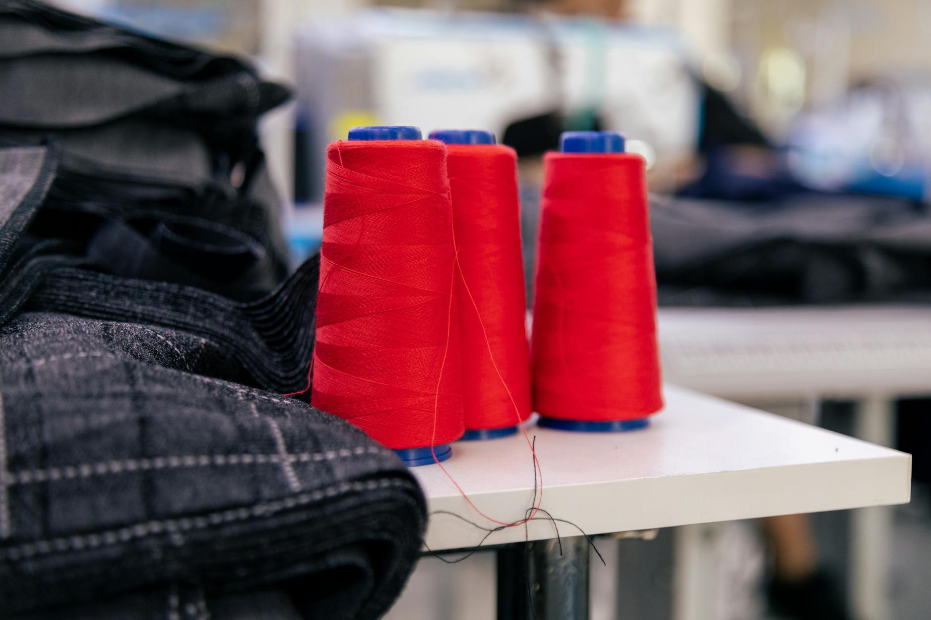Vibrant red thread spools on a table in a tailoring room. Ideal for sewing imagery.