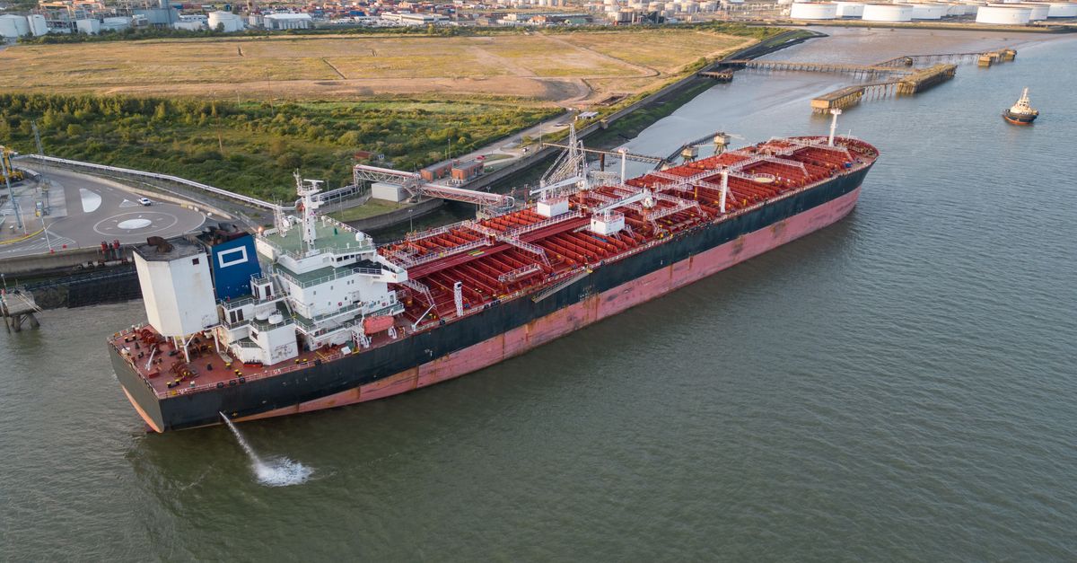 Aerial view of a large cargo ship docked in an industrial harbor, showcasing the vessel's capacity.
