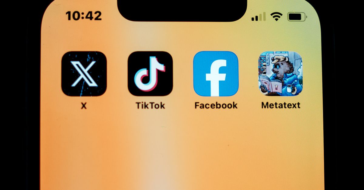 Close-up of smartphone displaying social media apps on a yellow background.