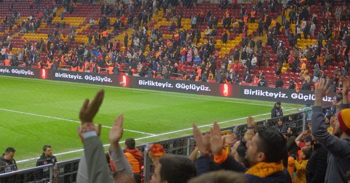 Passionate Galatasaray fans cheering during an Istanbul soccer match in a vibrant stadium.