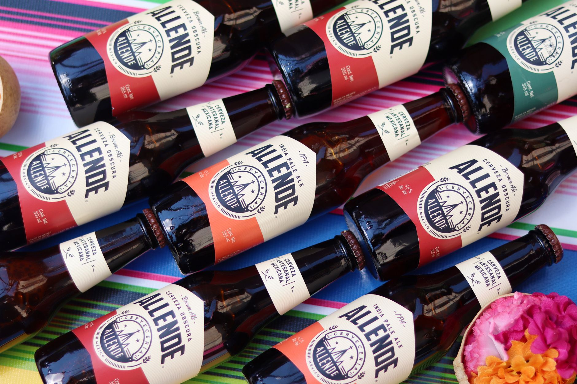 Assorted Allende beer bottles arranged on a colorful Mexican textile.