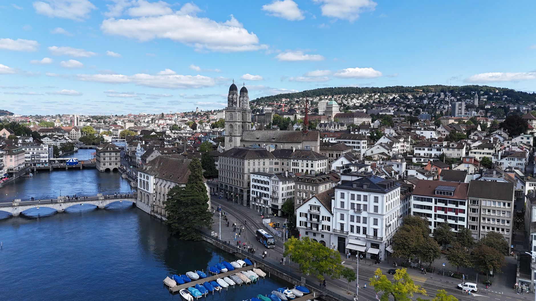 Aerial cityscape of Zurich, showcasing historic architecture, river, and Limmatquai under a vibrant blue sky.
