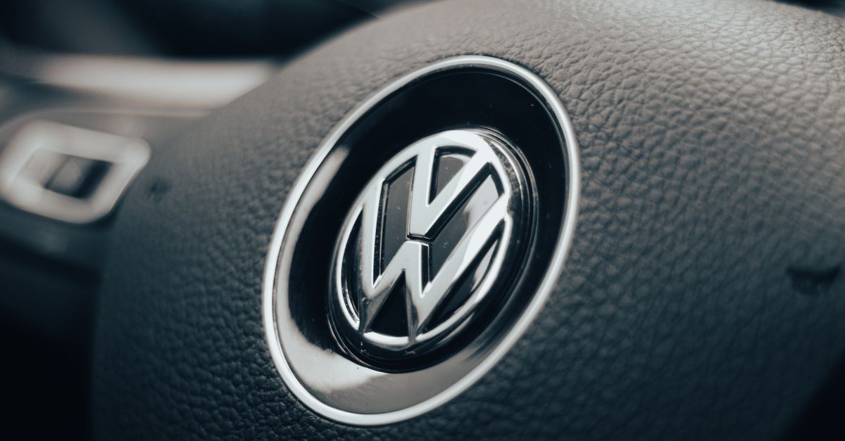 Detail of a Volkswagen steering wheel inside a vehicle's interior. Dark and moody lighting enhances the texture.