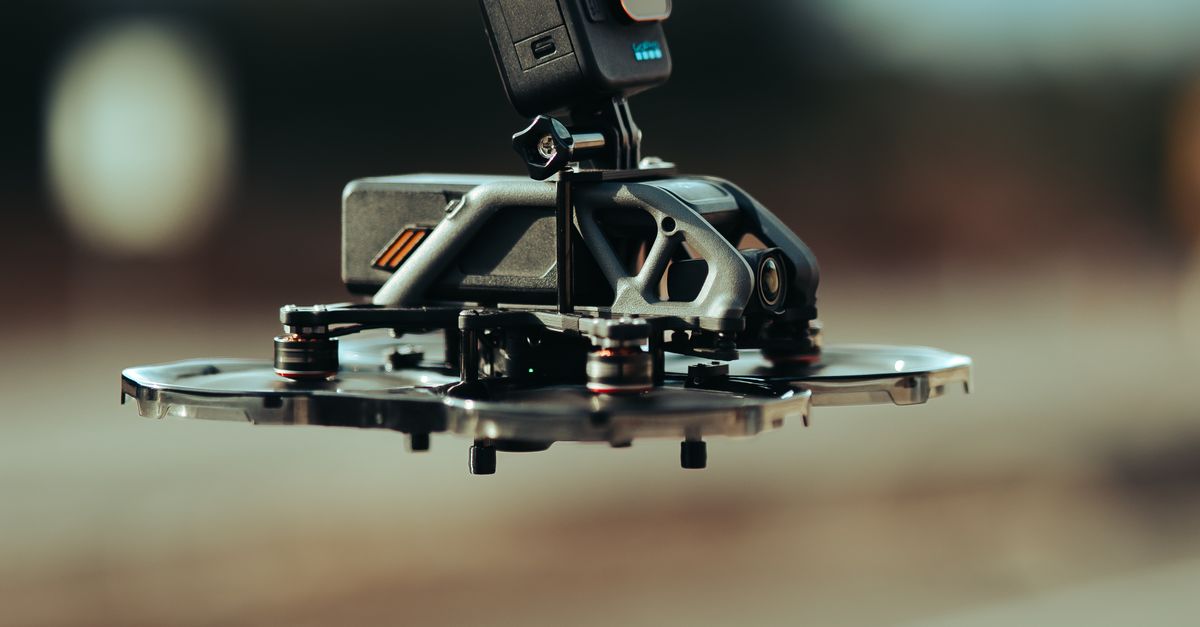 Close-up of a drone equipped with an action camera, flying outdoors in daylight.