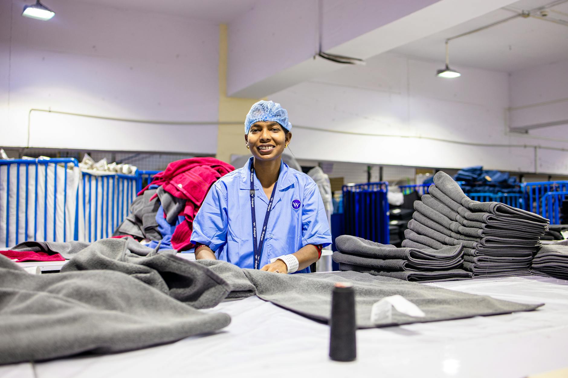 A happy textile worker stacks fabrics in a well-lit factory setting.