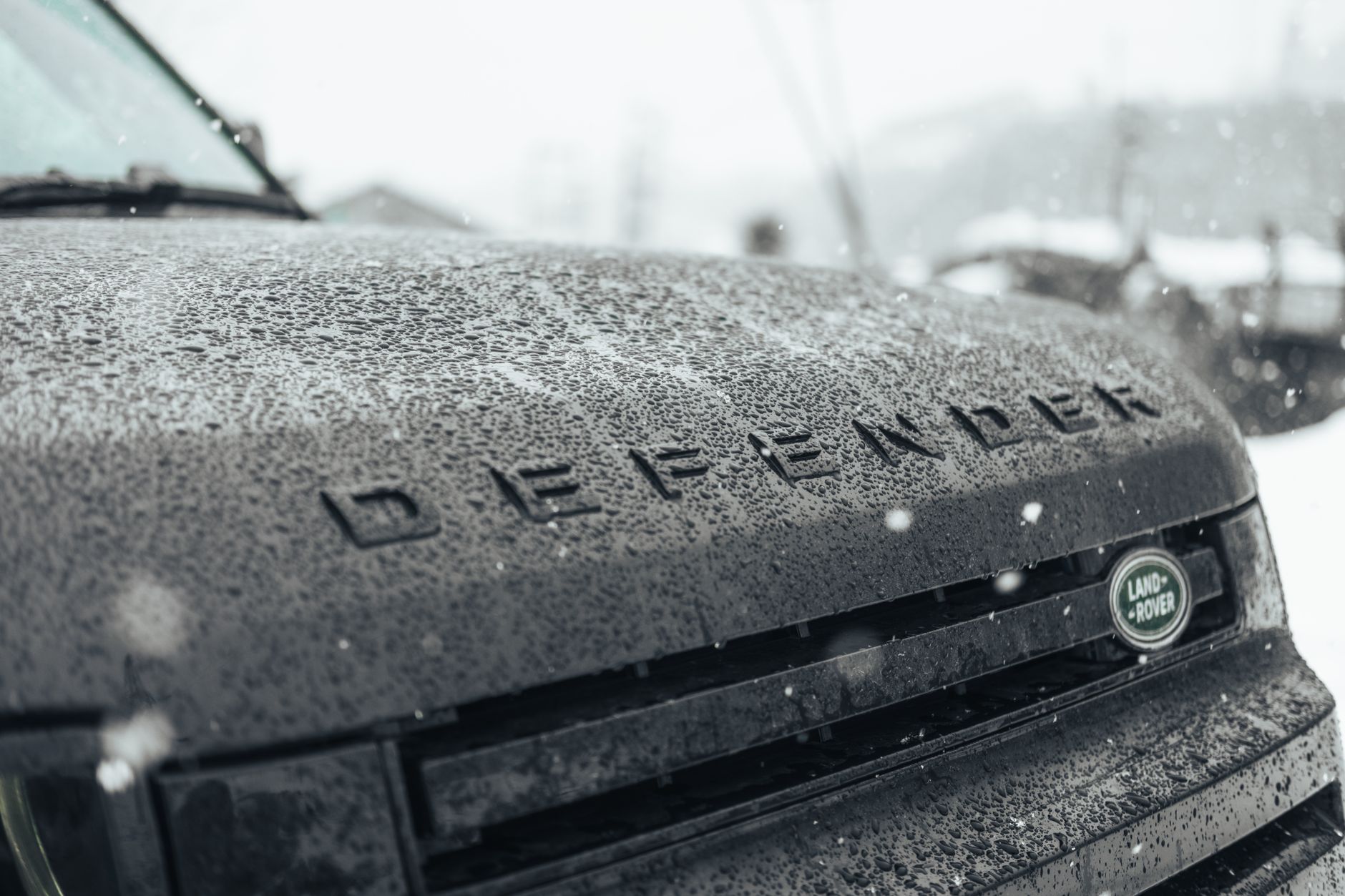 Snow-covered Land Rover Defender grille captured outdoors.