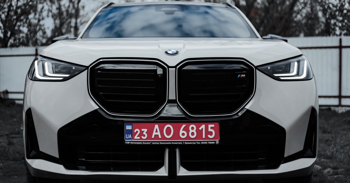 A sleek front view of a BMW car featuring a Ukrainian license plate outdoors.