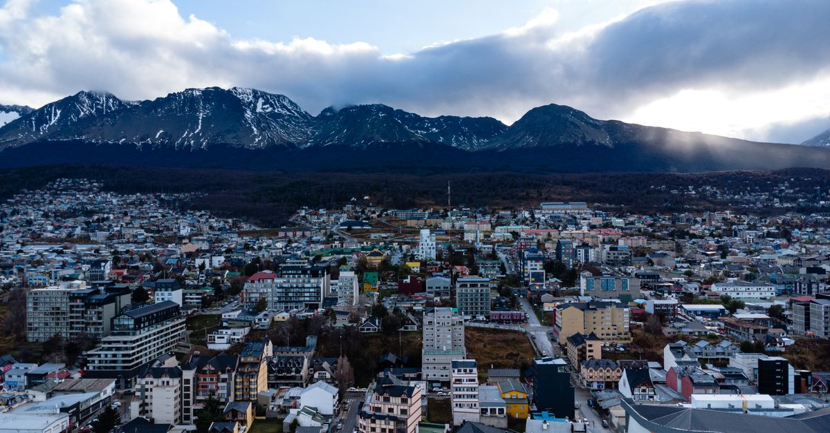 Explore the scenic cityscape of Ushuaia, Argentina, set against stunning mountains and dramatic skies.