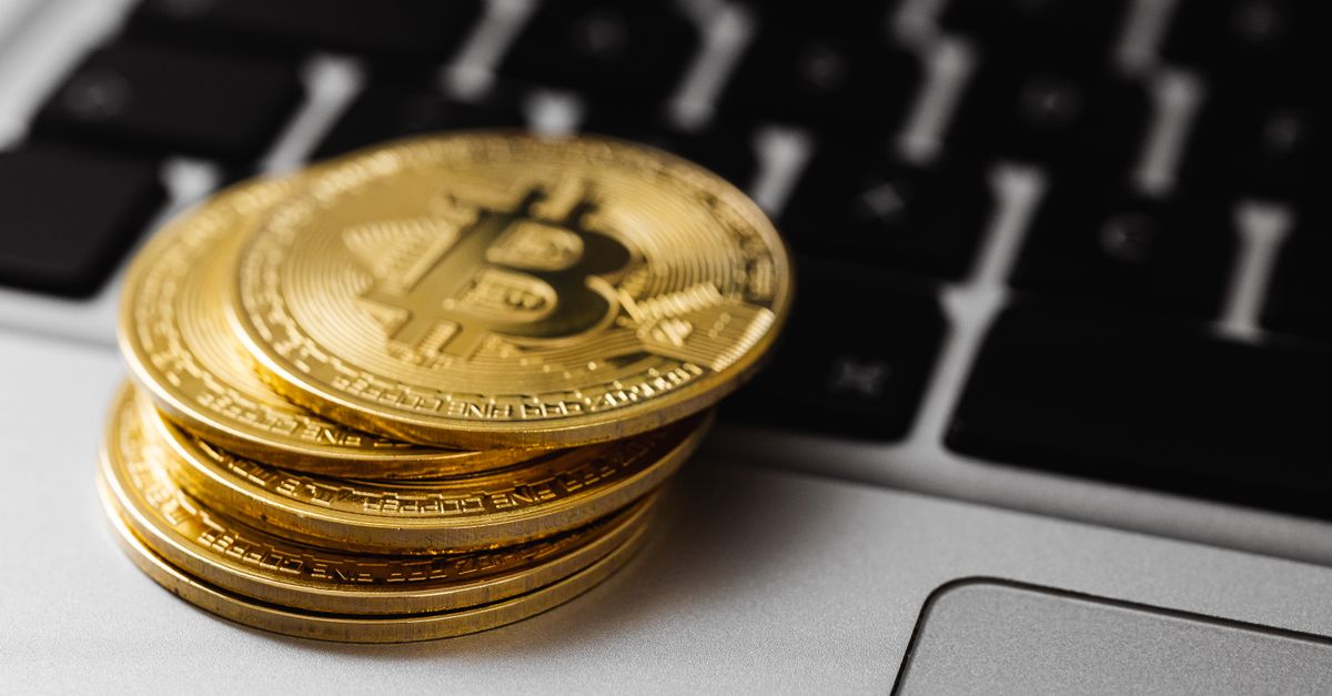 Stack of golden bitcoins on a laptop keyboard, symbolizing digital currency and wealth.