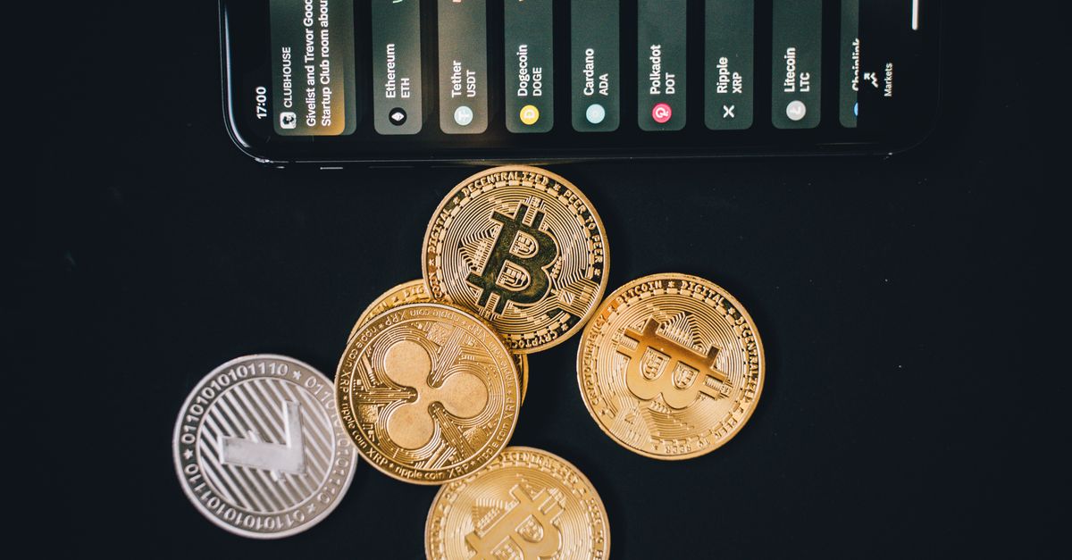 Close-up of various cryptocurrencies and a smartphone showing market trends.