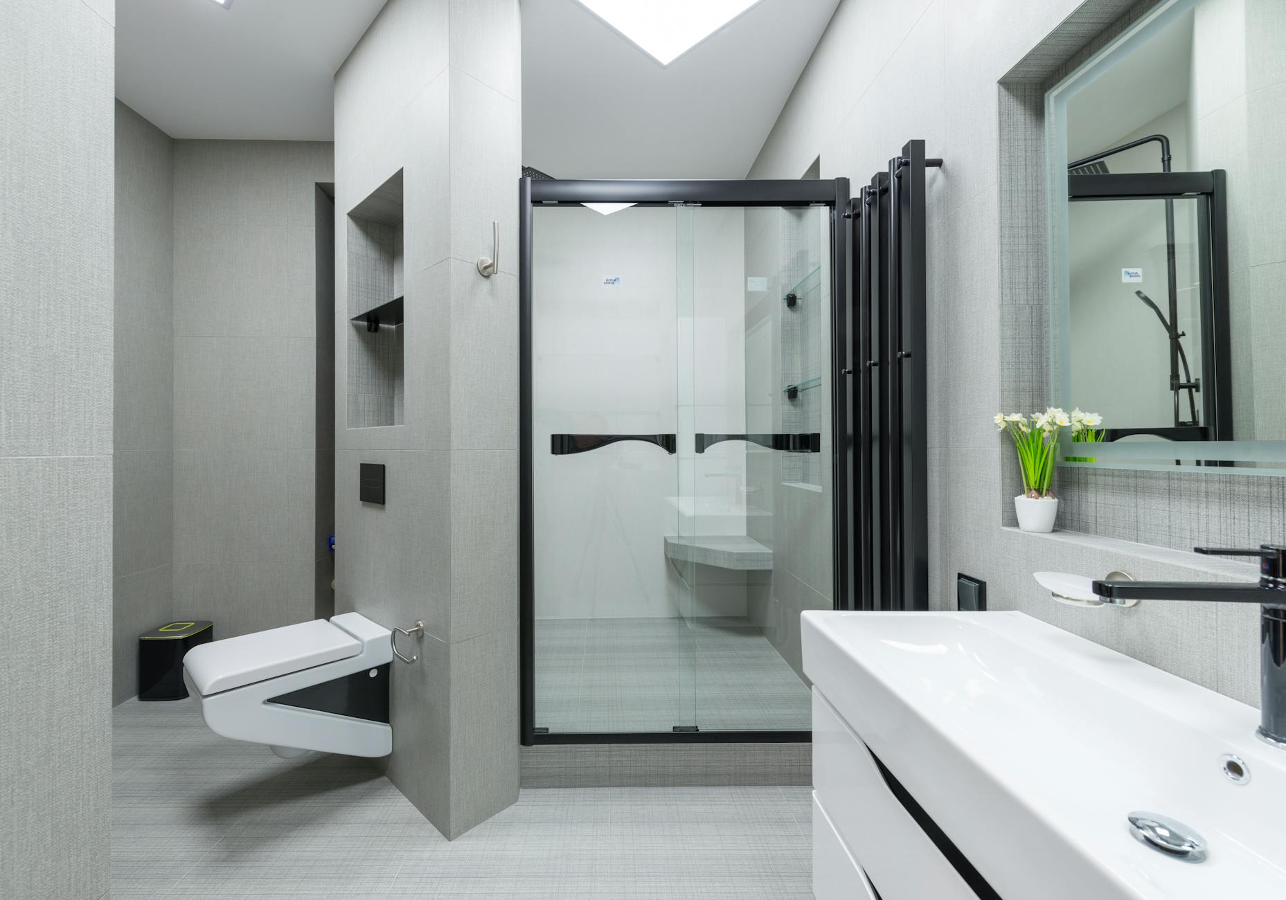 Sink with tap placed at wall with mirror in light spacious bathroom with toilet and glass shower cabin in apartment