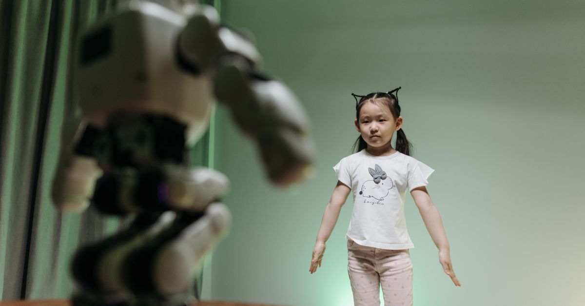 An Asian child interacts with a humanoid robot indoors, embracing innovation and play.