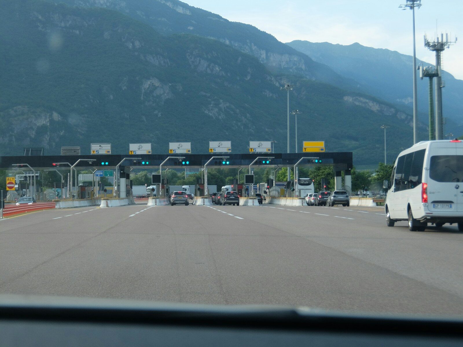Cars approaching a multi-lane toll booth with mountains in background.