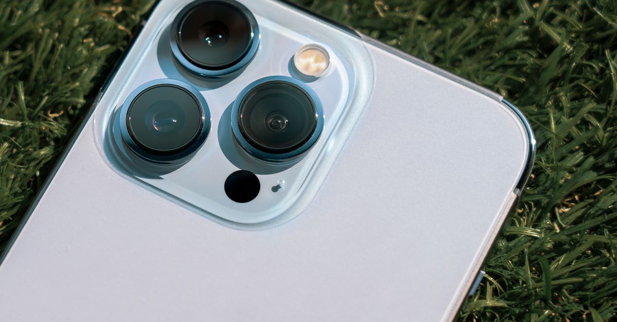 Detailed close-up of smartphone camera lenses on green grass background.