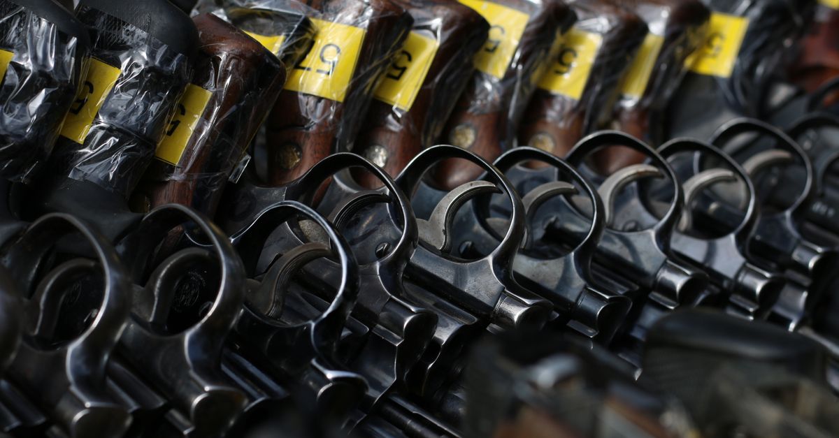 Close-up image of revolvers with yellow tags arranged on a rack.