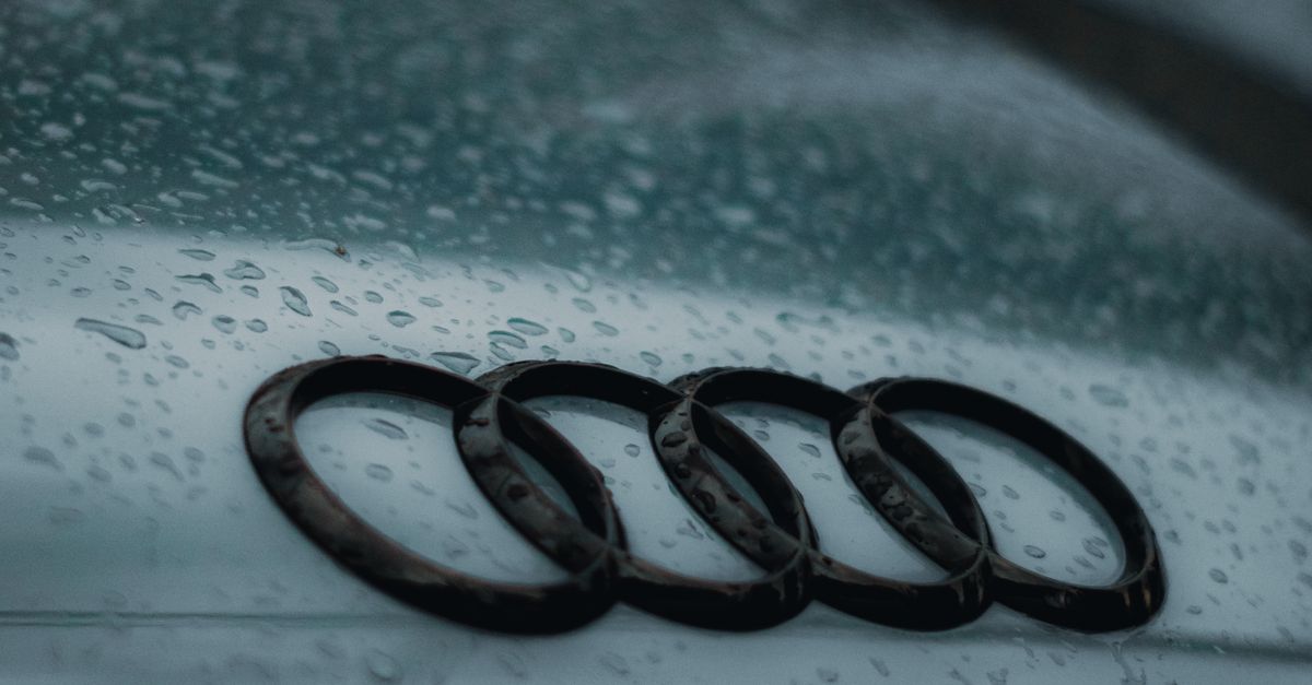Raindrops on the hood of an Audi car, showcasing the brand's emblem.