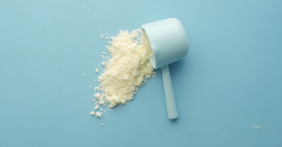 White powder spilled from a scoop on bright blue background. Clean and minimalistic food photo.