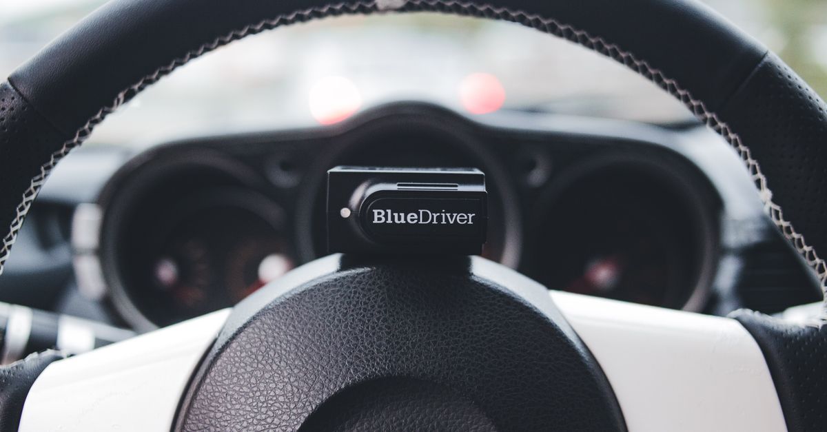 Close-up view of a BlueDriver device on a car steering wheel, highlighting automotive tech.