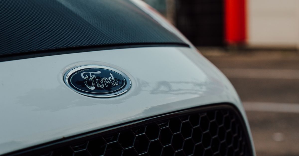 Detailed close-up image showcasing a white Ford car emblem on the vehicle's grille.