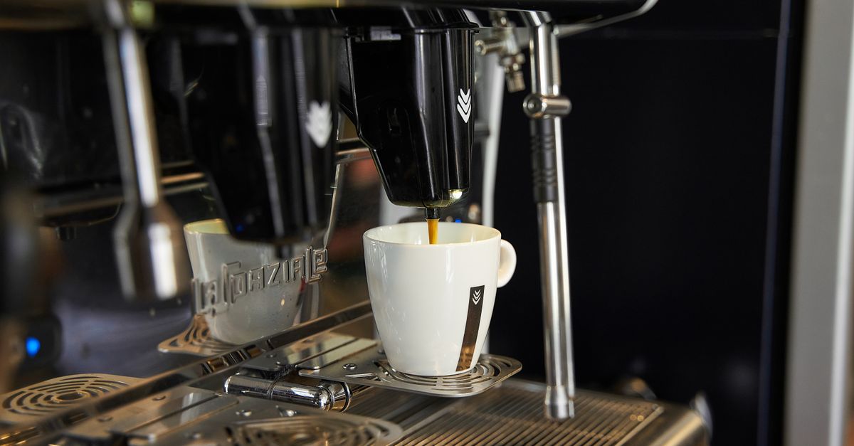 A detailed view of an espresso being poured from a coffee machine into a white cup, capturing the essence of coffee art.