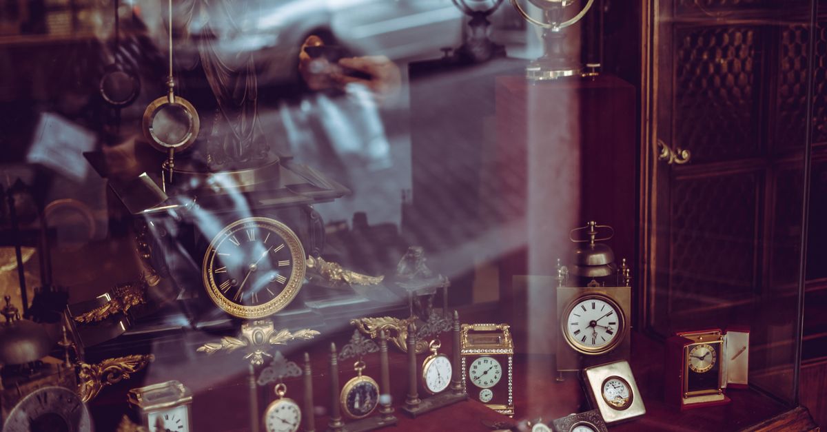 Vintage clock collection showcased in a Roman shop with reflective glass and elegant designs.