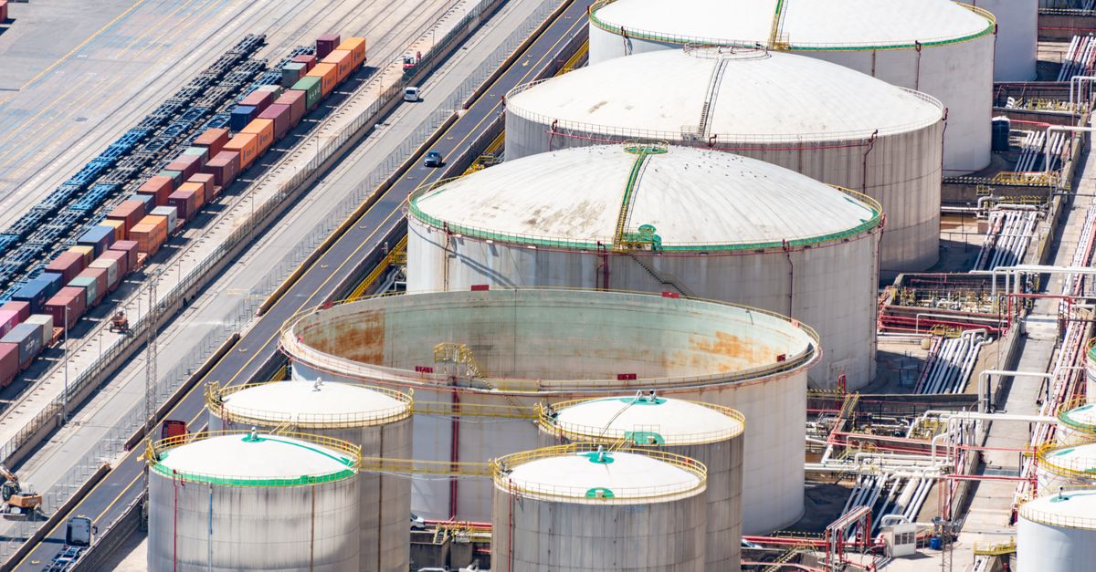 Aerial shot of large oil storage tanks in an industrial district with adjacent railway tracks.