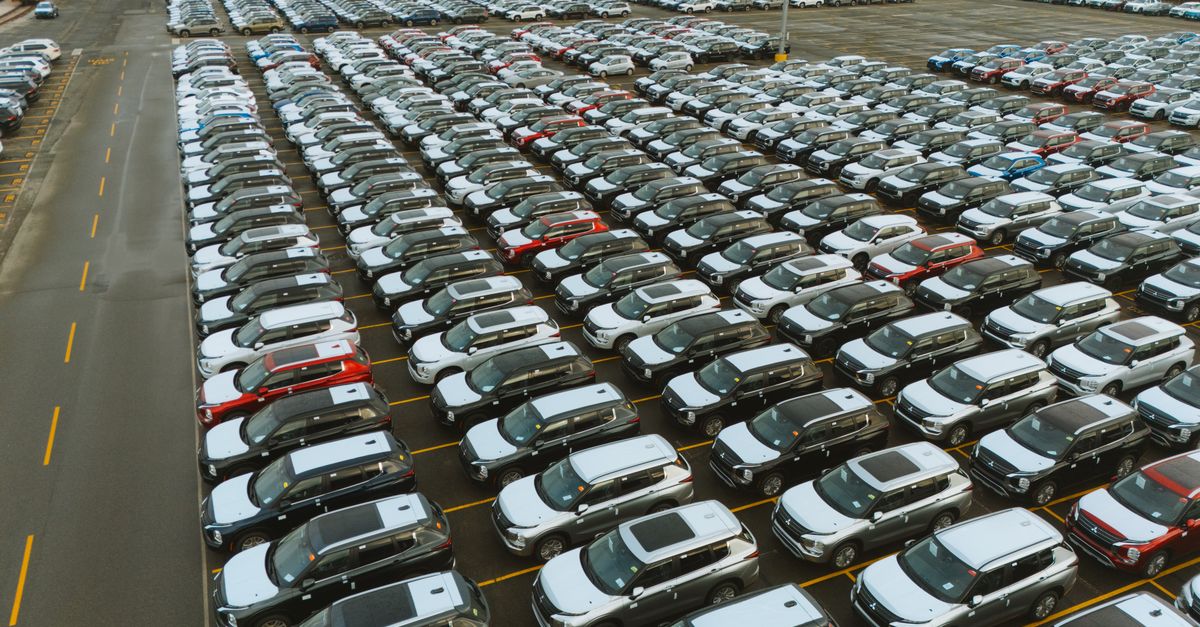 Aerial shot of an extensive car parking lot filled with new vehicles ready for distribution.