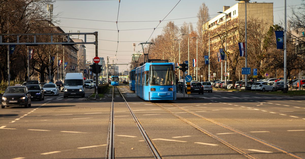 Blue tram traversing a busy street in Zagreb, Croatia's urban landscape.