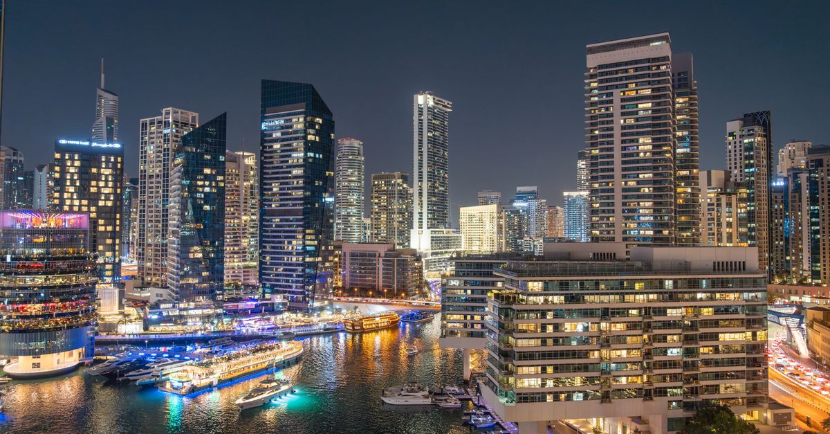 Stunning night view of Dubai Marina with illuminated skyscrapers and reflections on the water.