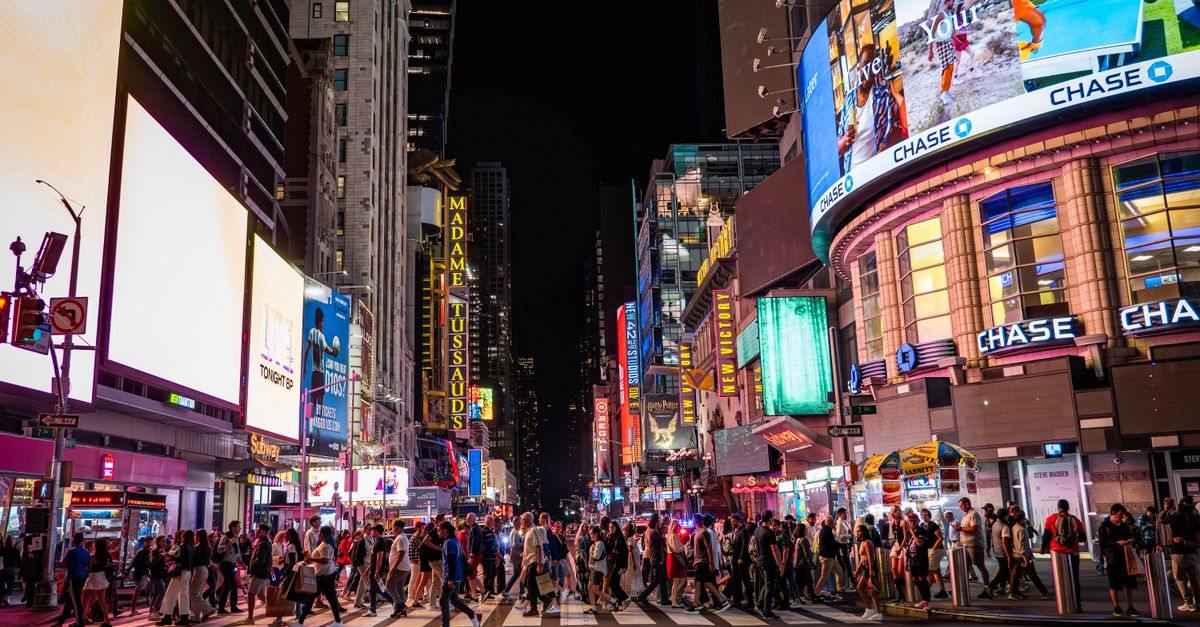 A lively view of Times Square at night with bustling crowds, bright billboards, and iconic landmarks.