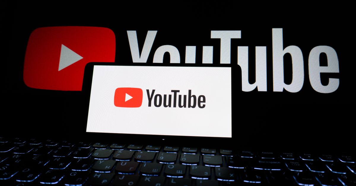 Close-up of YouTube logo displayed on a laptop screen in a dark environment.