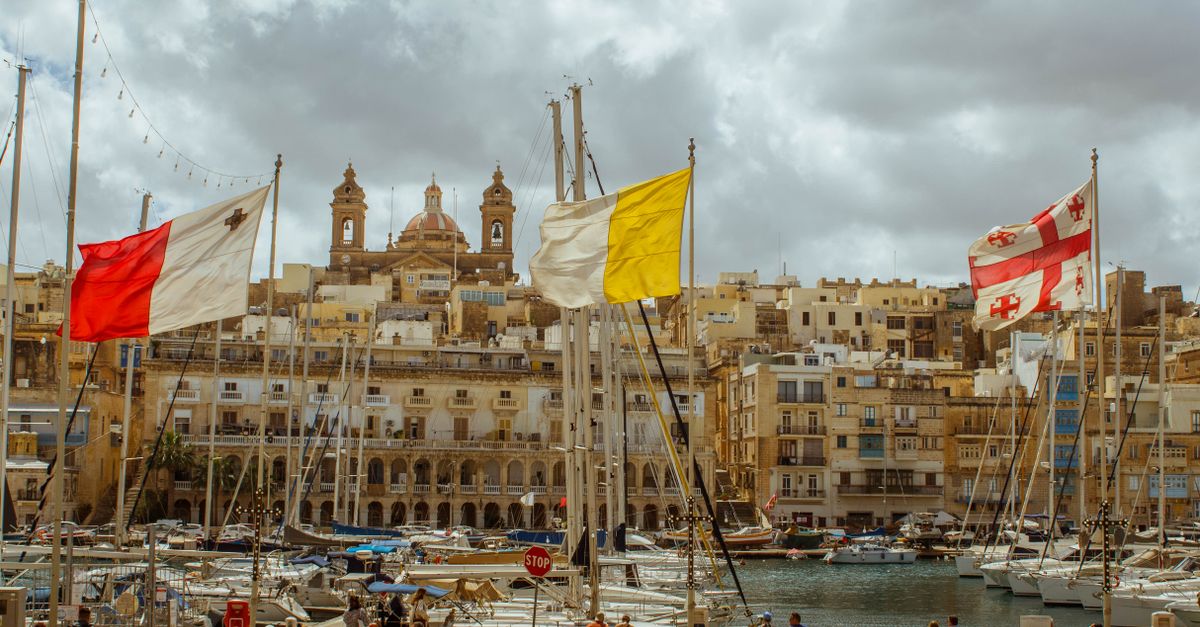 Beautiful view of a harbor in Malta with colorful flags and boats, capturing the architectural charm and vibrant atmosphere.