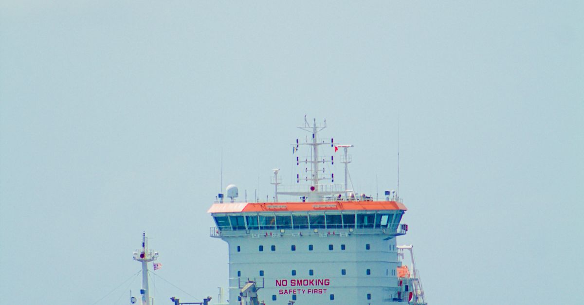 A large cargo ship navigates calm ocean waters under a clear sky. Perfect for maritime themes.