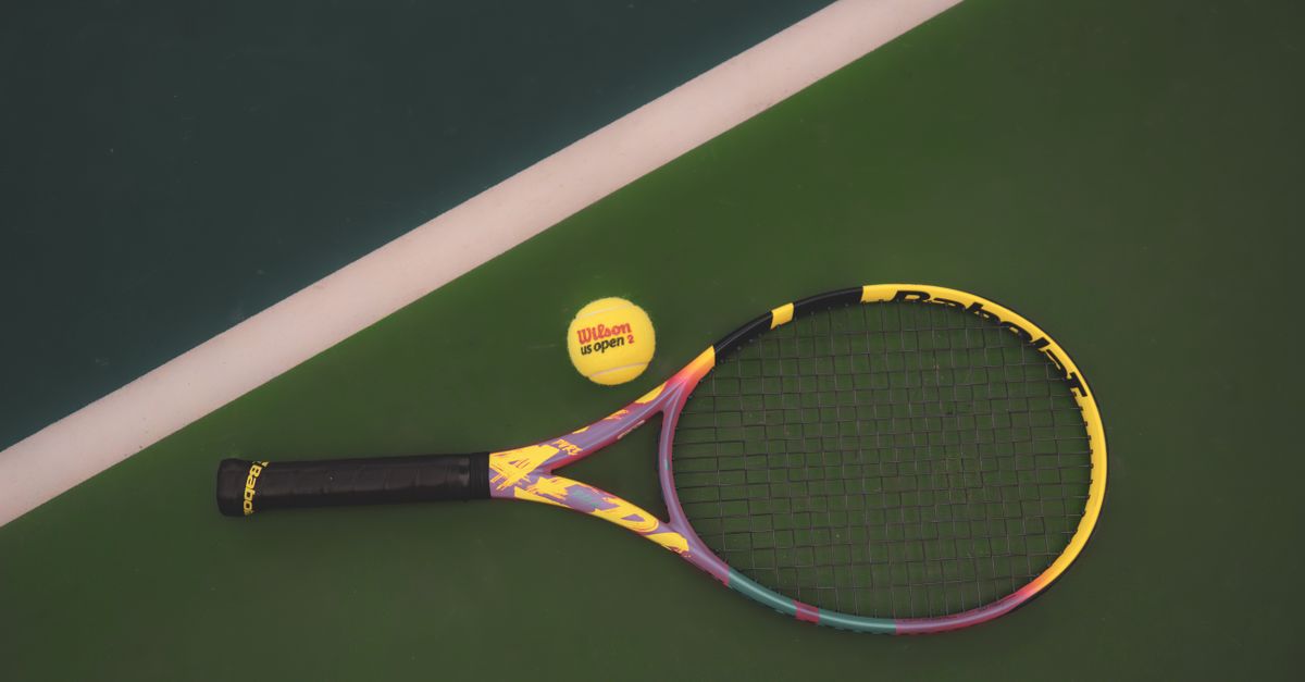 Tennis racket and ball on a vibrant green court, ready for a match.