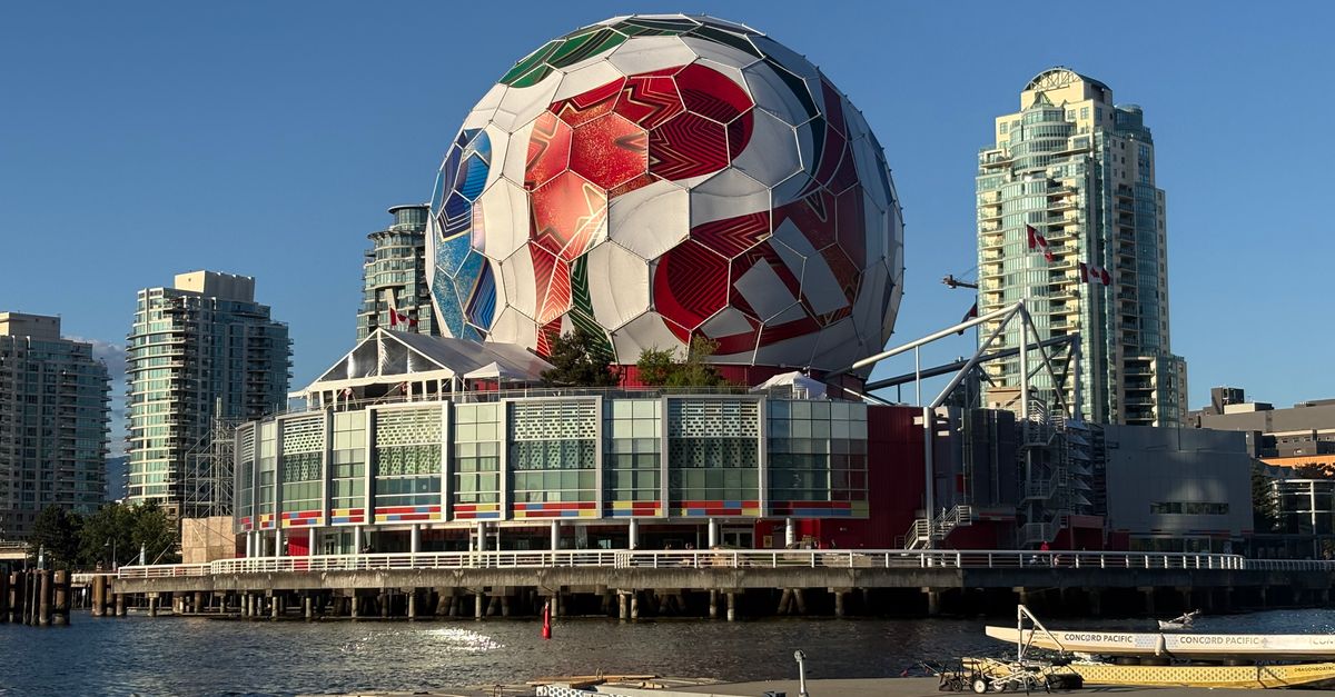 A massive soccer ball decorates Science World, set against Vancouver's iconic skyline and waterscape.