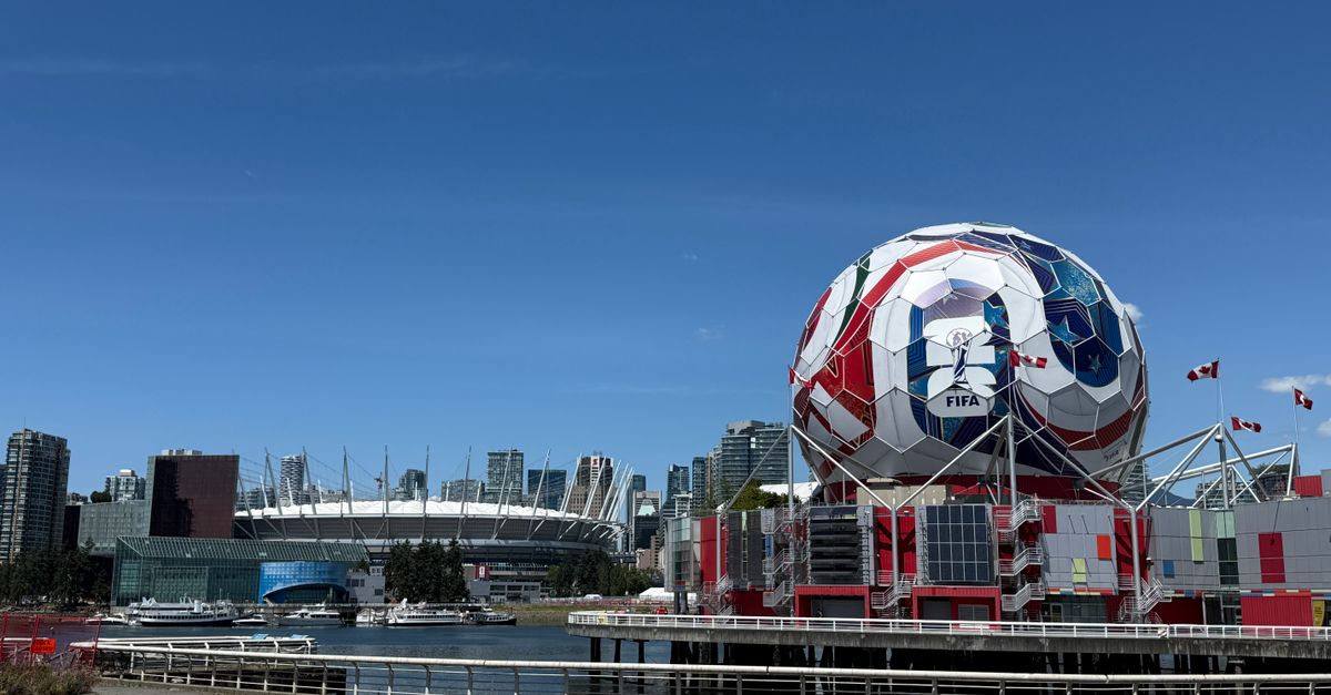 View of Vancouver's Science World featuring FIFA display and BC Place Stadium under a clear blue sky.