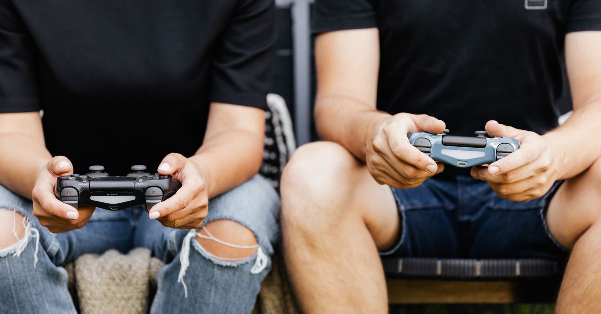 Happy couple enjoying video games together with controllers on a sofa.