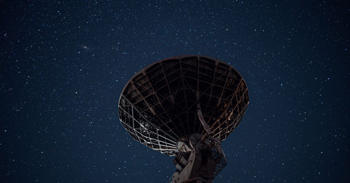 From below of high radio telescope under sky with glowing stars in dark night